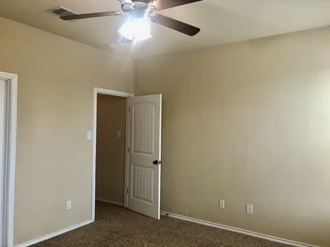 an empty room with a ceiling fan and a window