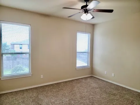 an empty room with windows and fan