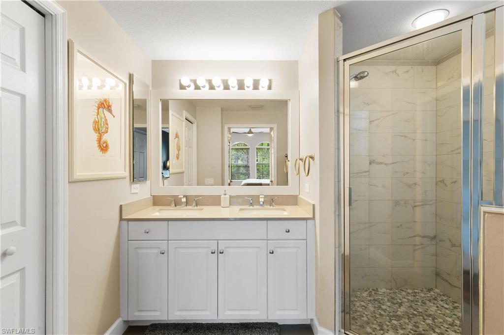 10021 Heather Lane, Unit 803 Naples, FL 34119 - Photo 16 of 41 a bathroom with a shower sink and mirror