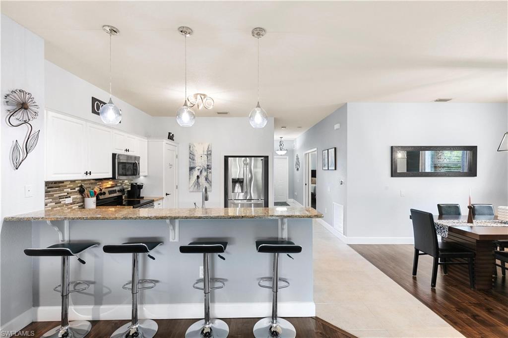 10021 Heather Lane, Unit 803 Naples, FL 34119 - Photo 5 of 41 a kitchen with stainless steel appliances kitchen island granite countertop a dining table chairs and a refrigerator