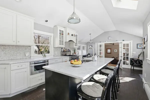 a kitchen with a sink a stove and chairs with wooden floor