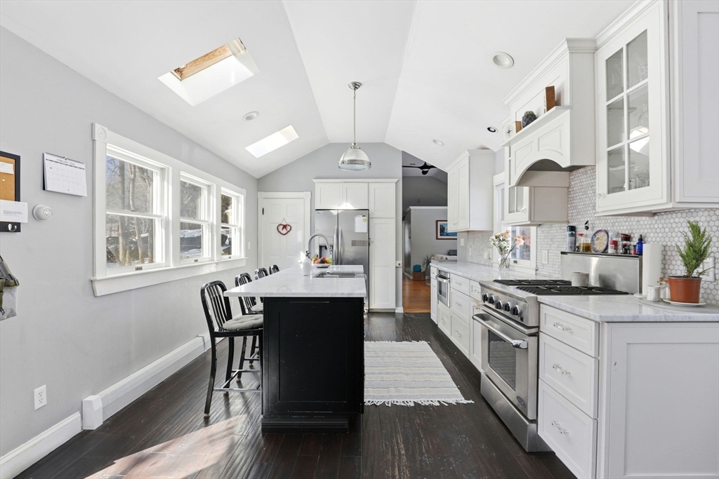 327 Country Way Scituate, MA 02066 - Photo 16 of 39 a kitchen with stainless steel appliances granite countertop a stove a sink dishwasher a dining table and chairs with wooden floor