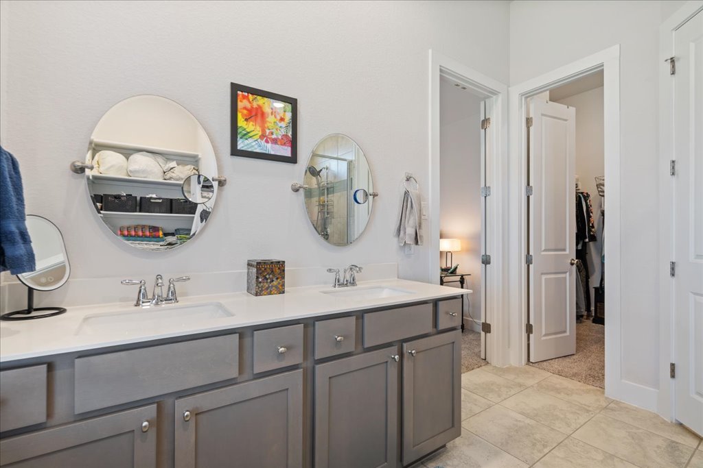 7912 Prairie Rye Drive Lago Vista, TX 78645 - Photo 17 of 37 Primary ensuite bath featuring a spacious double vanity, modern lighting, and a large walk-in tiled shower with glass enclosure. Enjoy ample storage and natural light in this serene, spa-like retreat.