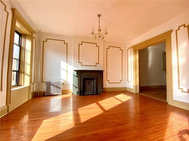 a view of a livingroom with a fireplace wooden floor and windows