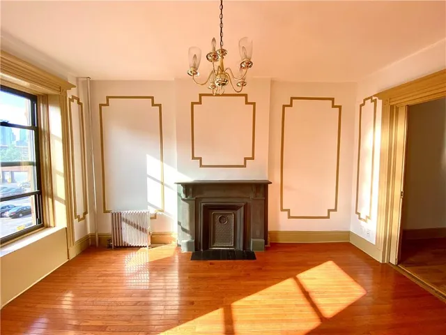 a view of a room with wooden floor fireplace and windows