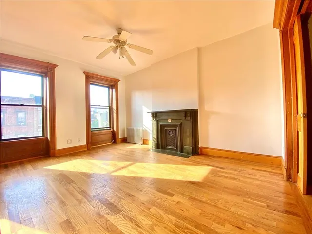 a view of an empty room with window and wooden floor