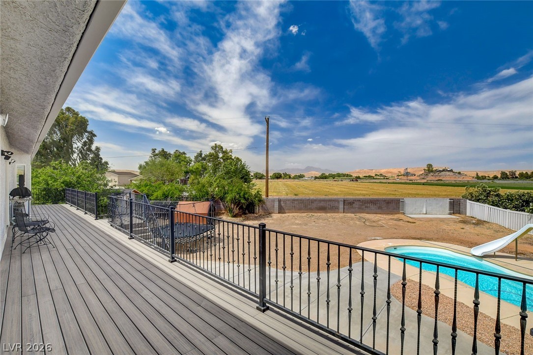 4362 Thistle Street Logandale, NV 89021 - Photo 71 of 99 A spacious deck overlooks a private swimming pool, offering expansive views of distant fields and mesas under a vast sky.