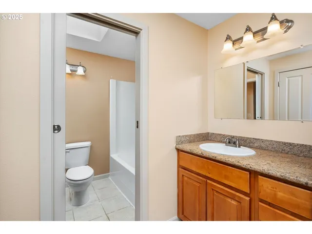 a bathroom with a granite countertop sink toilet and mirror