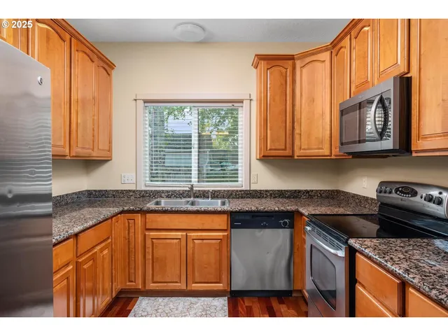 a kitchen with stainless steel appliances granite countertop a stove a sink dishwasher and cabinets with wooden floor