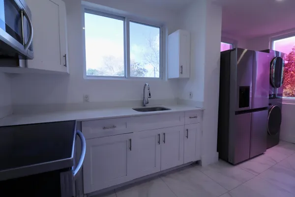 a kitchen with stainless steel appliances a sink cabinets and a window