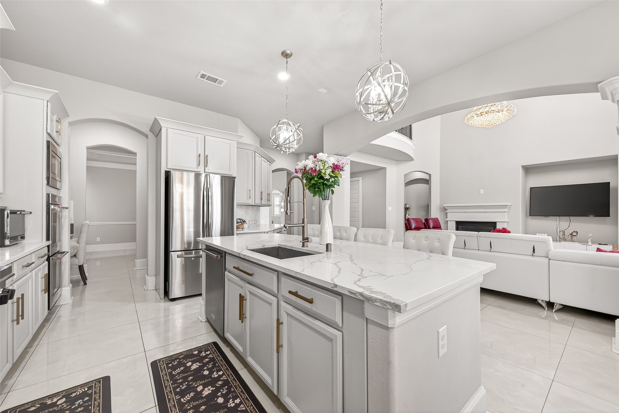 1122 Thyme Rise Lane Richmond, TX 77406 - Photo 24 of 50 a large white kitchen with a large island stainless steel appliances a chandelier and living room view
