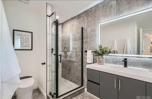 a bathroom with a shower sink vanity mirror and toilet