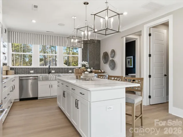 a kitchen with stainless steel appliances kitchen island granite countertop a table chairs and a refrigerator