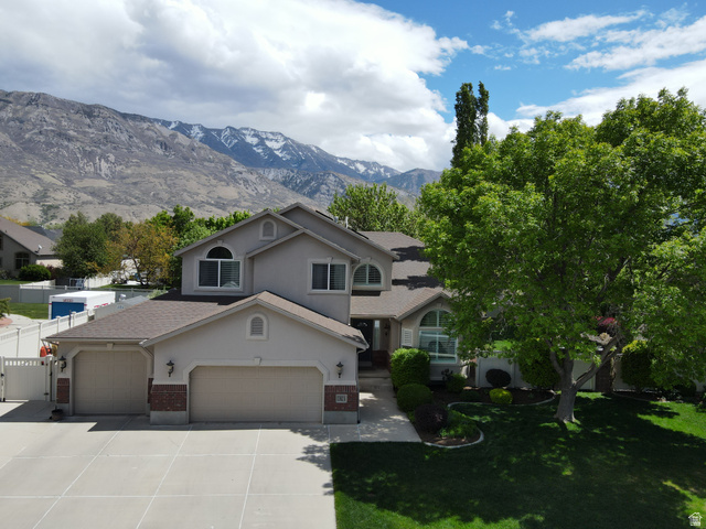 1382 Narra Place Pleasant Grove, UT 84062 - Photo 1 of 1 View of front of house featuring stucco siding, concrete driveway, a mountain view, a front lawn, and brick siding