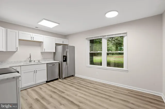 a kitchen with granite countertop a refrigerator sink and cabinets