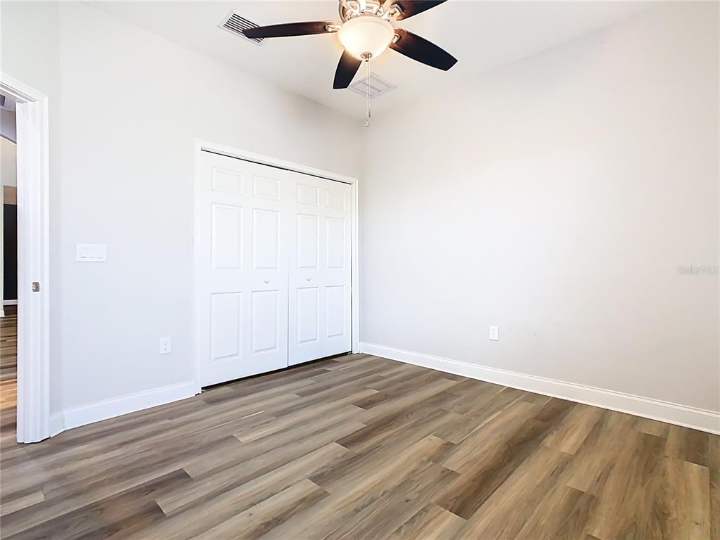 1918 Berry Road Plant City, FL 33567 - Photo 35 of 53 an empty room with wooden floor ceiling fan and windows