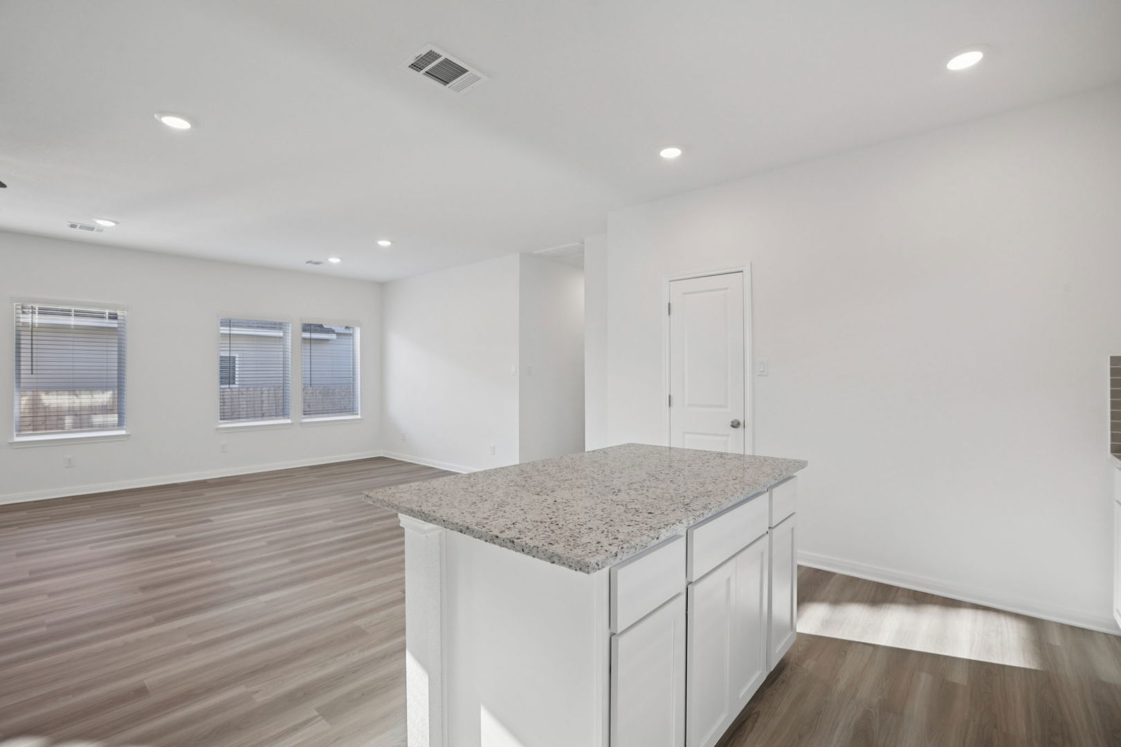 120 Outlaw Drive Jarrell, TX 76537 - Photo 4 of 16 Kitchen featuring white cabinets, light stone counters, a center island, dark wood-type flooring, and recessed lighting