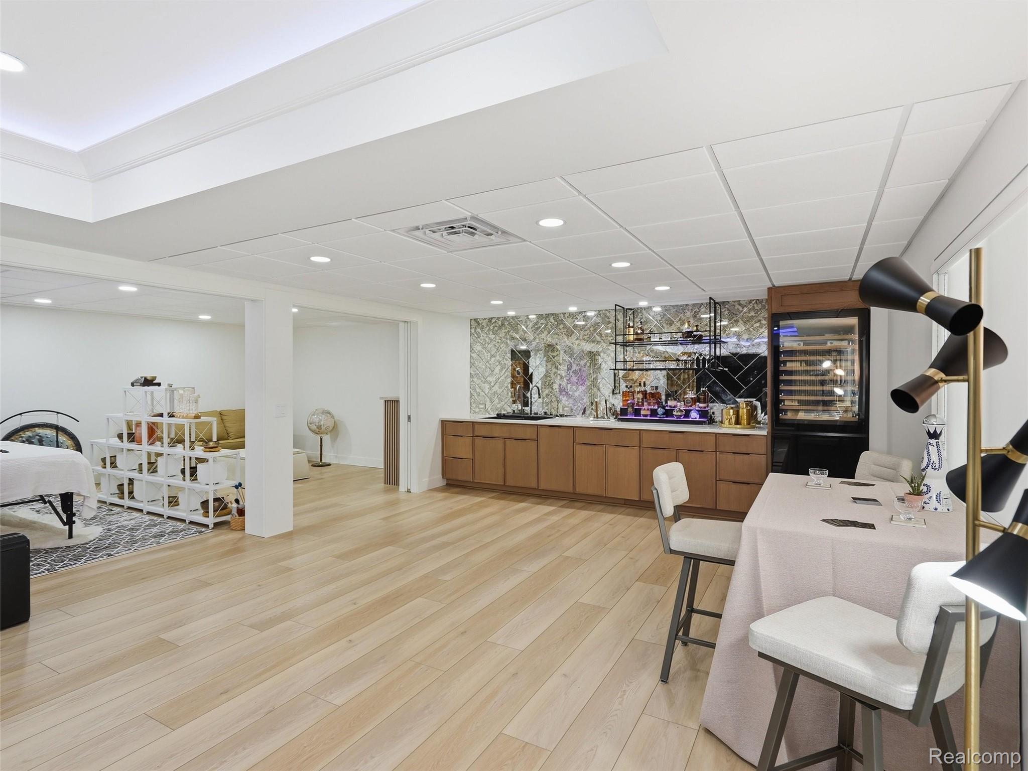 3007 28 Mile Road Washington, MI 48094 - Photo 48 of 69 Spacious interior featuring light wood-finish flooring, a built-in bar with wood cabinetry and patterned backsplash, a built-in beverage refrigerator, and recessed lighting