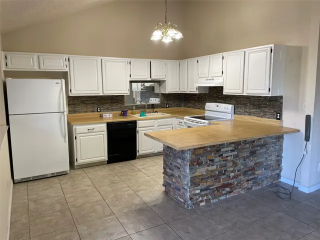 a kitchen with stainless steel appliances granite countertop a stove top oven a refrigerator a sink and white cabinets