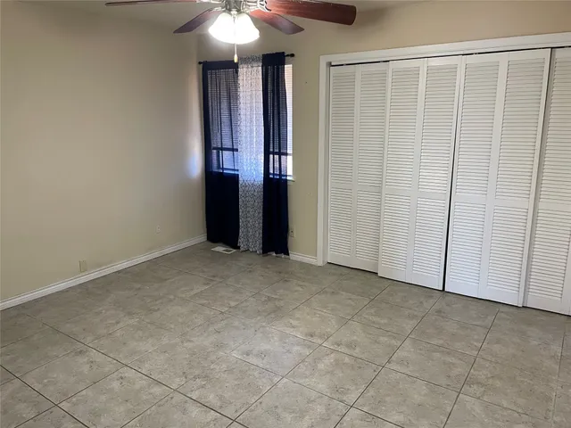 a view of an empty room with window and chandelier fan