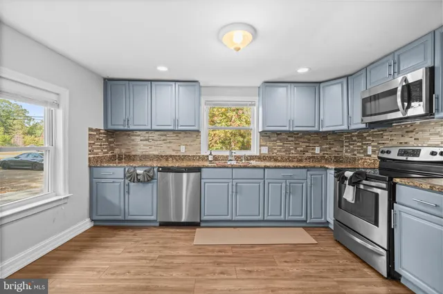 a kitchen with granite countertop wooden cabinets a stove a sink and a window