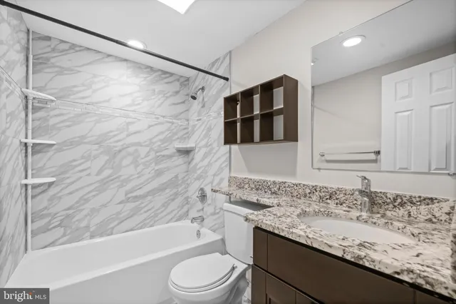 a bathroom with a granite countertop sink toilet and shower
