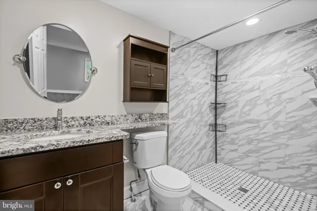 a bathroom with a granite countertop sink toilet and shower