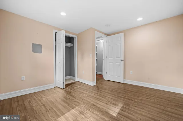 a view of an empty room with wooden floor and closet