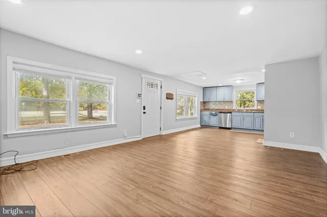 a view of empty room with kitchen and window