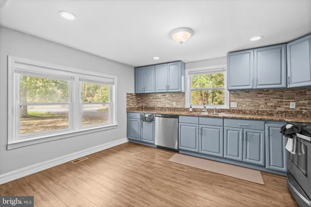 a kitchen with granite countertop wooden floors wooden cabinets a sink and a window