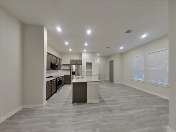 a view of kitchen with kitchen island microwave oven stove and cabinets