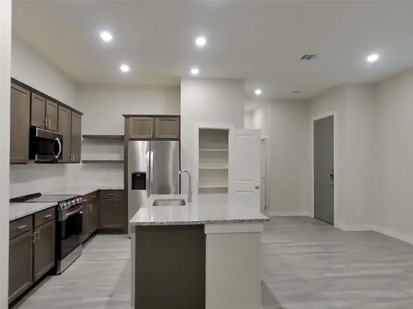 a kitchen with stainless steel appliances granite countertop a sink and stove top oven with wooden floor