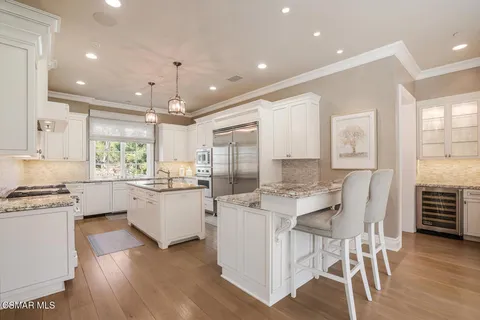 a kitchen with center island wooden floor and stainless steel appliances