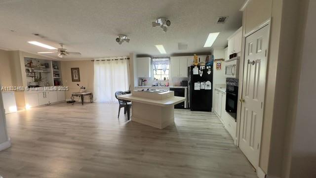 35250 Southwest 177th Court, Unit 136 Homestead, FL 33034 - Photo 11 of 18 a large white kitchen with kitchen island a refrigerator a sink a dining table and chairs