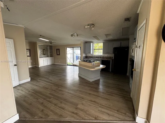 a living room with stainless steel appliances furniture a refrigerator and a view of kitchen