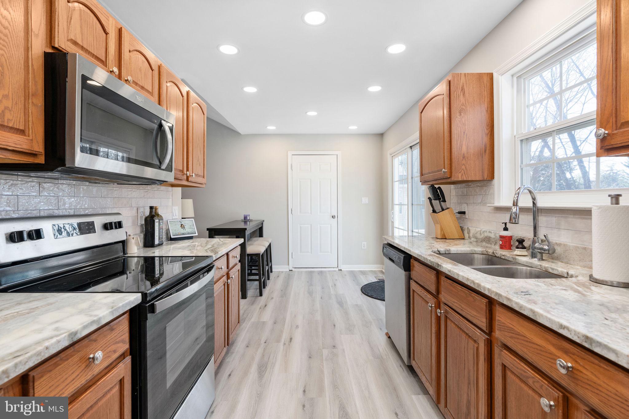 219 Santa Maria Avenue Colonial Beach, VA 22443 - Photo 16 of 52 a kitchen with stainless steel appliances granite countertop a stove a sink dishwasher and a microwave oven with wooden floor