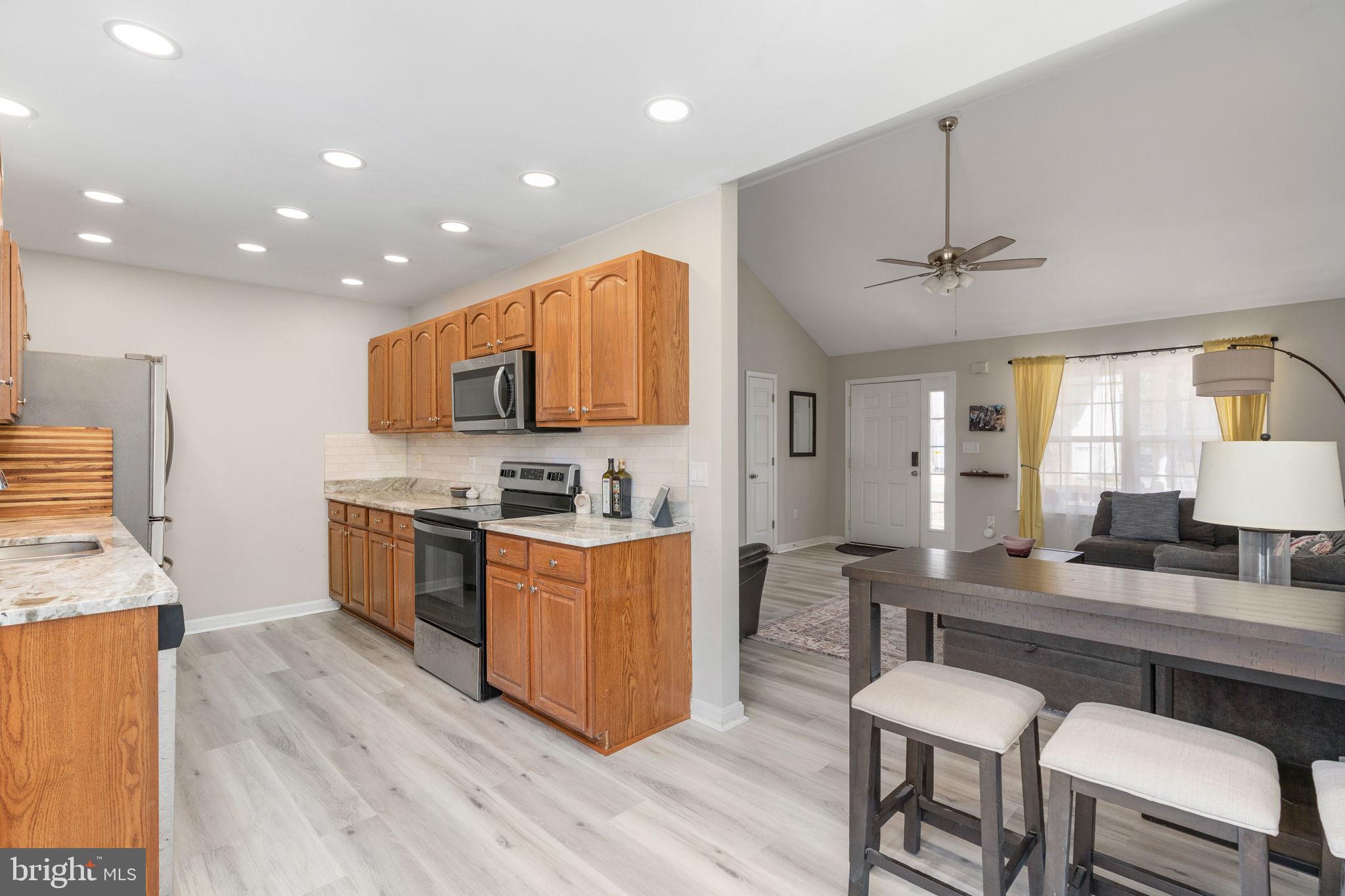 219 Santa Maria Avenue Colonial Beach, VA 22443 - Photo 10 of 52 a kitchen with stainless steel appliances granite countertop wooden cabinets a sink a stove a dining table and chairs