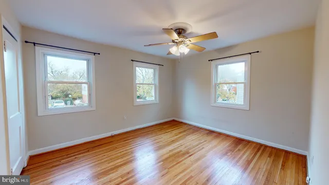 a view of empty room with wooden floor and fan