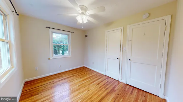 a view of empty room with wooden floor and fan