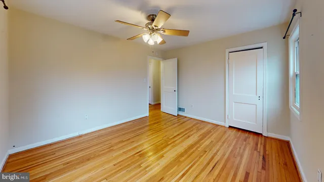 a view of an empty room with wooden floor and a chandelier fan