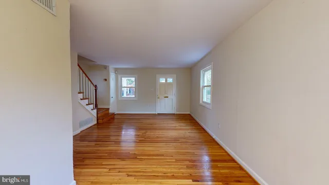 a view of an empty room with window and wooden floor
