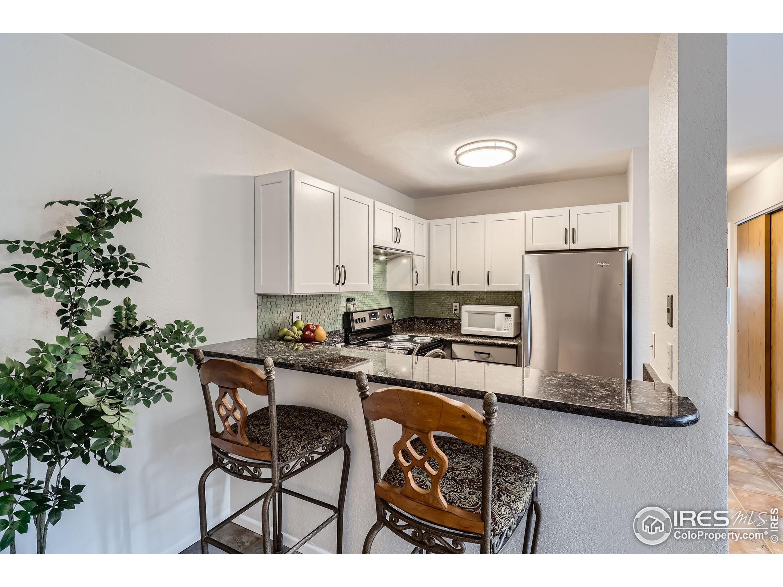3515 28th Street, Unit 108 Boulder, CO 80301 - Photo 8 of 29 a kitchen with stainless steel appliances a microwave a stove a refrigerator a sink a dining table and chairs with wooden floor