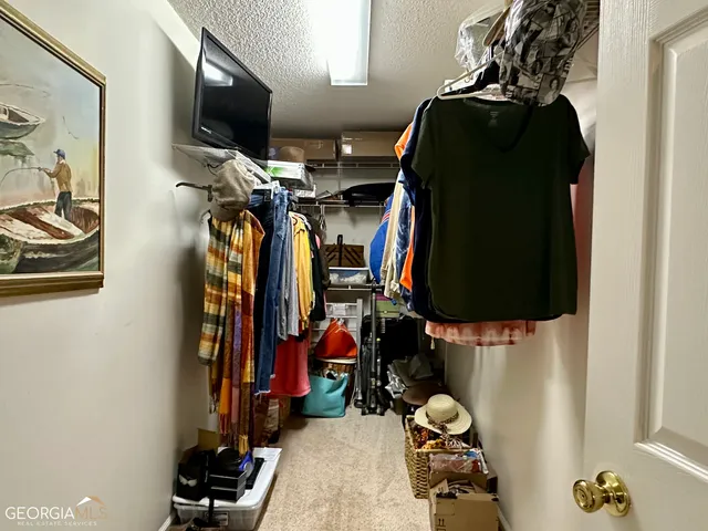 a view of walk in closet with clothes and shoes