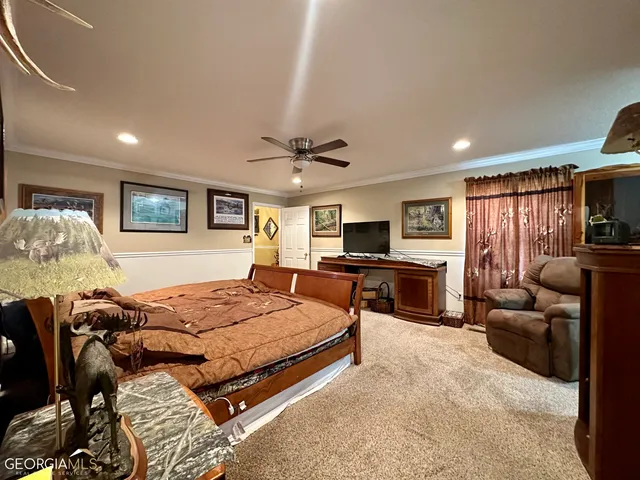 a spacious bedroom with a bed a couch and a flat tv screen on the dresser