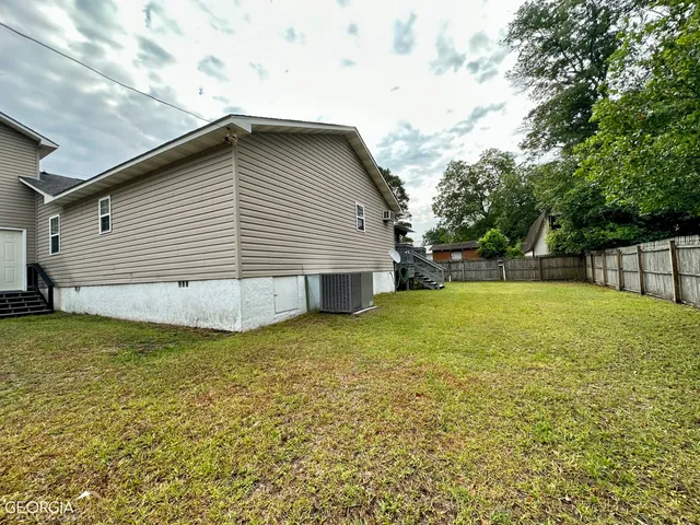 a backyard of a house with plants and large tree