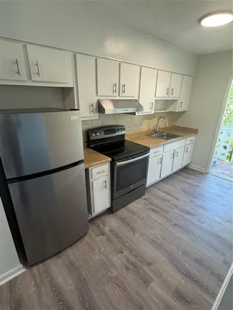 a kitchen with granite countertop a refrigerator stove top oven and sink