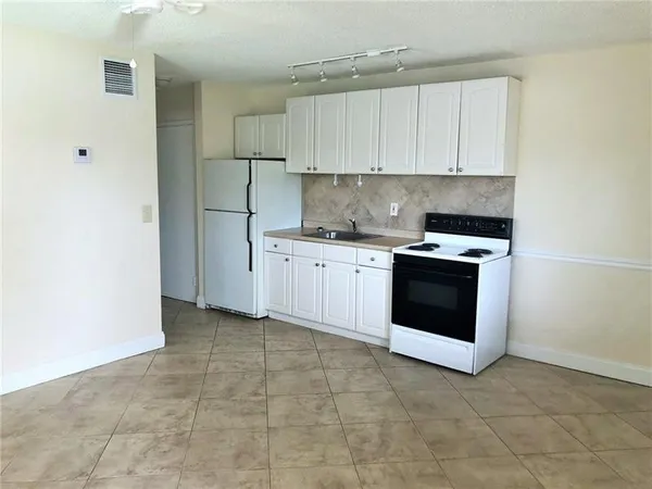a kitchen with granite countertop white cabinets and white appliances