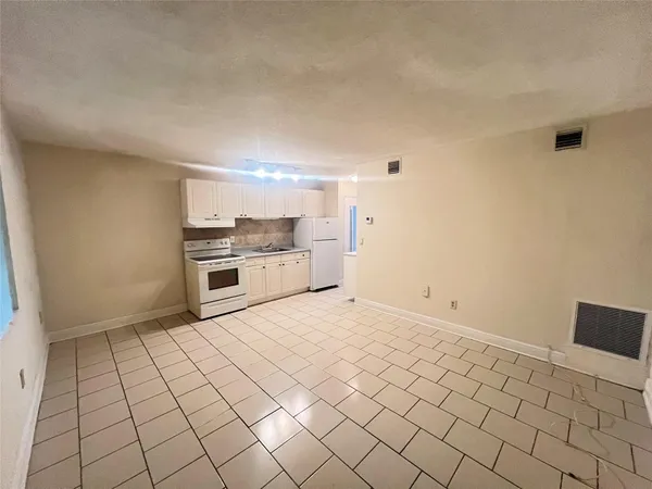 a view of empty room with kitchen