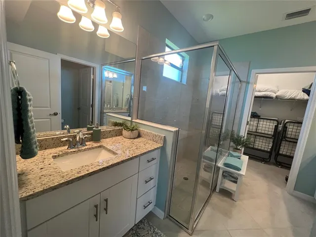 a bathroom with a granite countertop sink a mirror and a shower