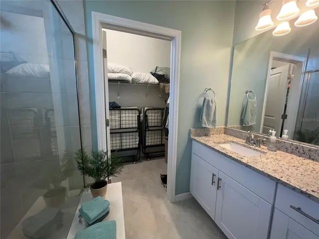 a spacious bathroom with a granite countertop sink a mirror and a shower